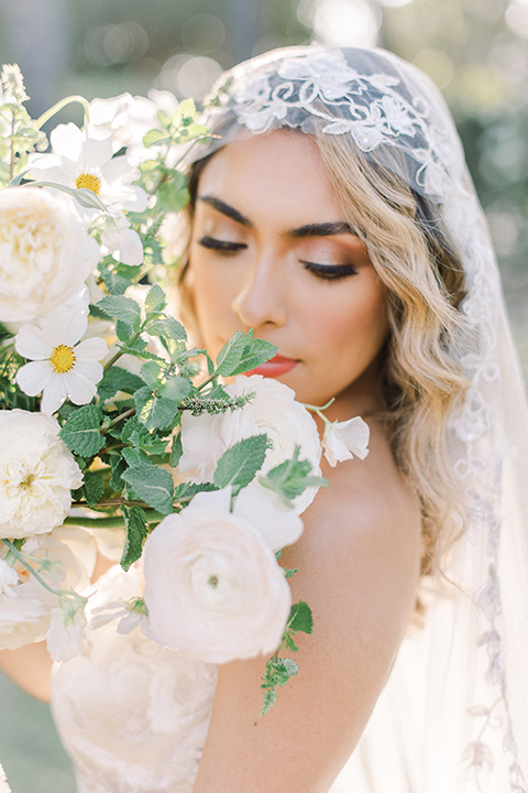  a romantic garden wedding at a Spanish inspired venue with the bride in a lace gown and the groom in a tan suit – bride with her veil on 