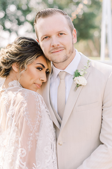  a romantic garden wedding at a Spanish inspired venue with the bride in a lace gown and the groom in a tan suit – couple close up