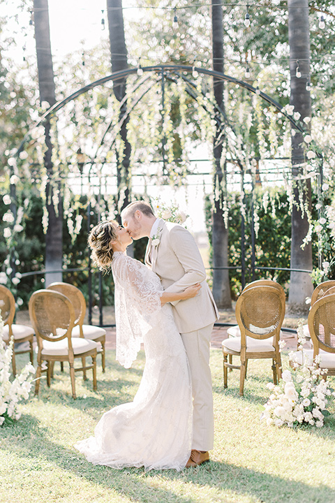  a romantic garden wedding at a Spanish inspired venue with the bride in a lace gown and the groom in a tan suit – ceremony couple