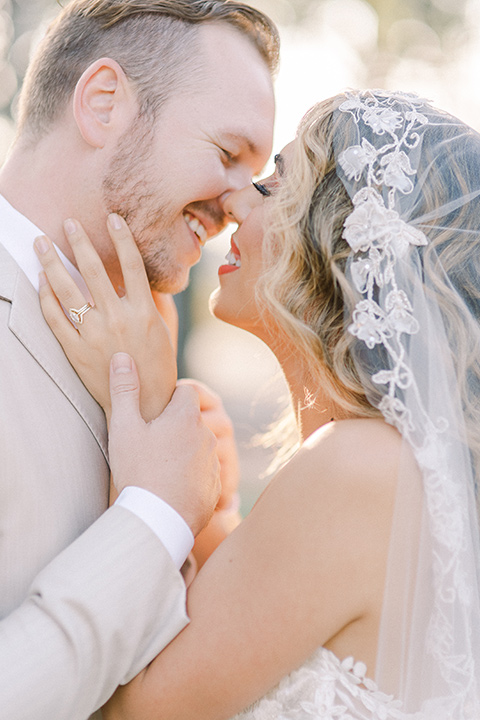  a romantic garden wedding at a Spanish inspired venue with the bride in a lace gown and the groom in a tan suit – couple kissing