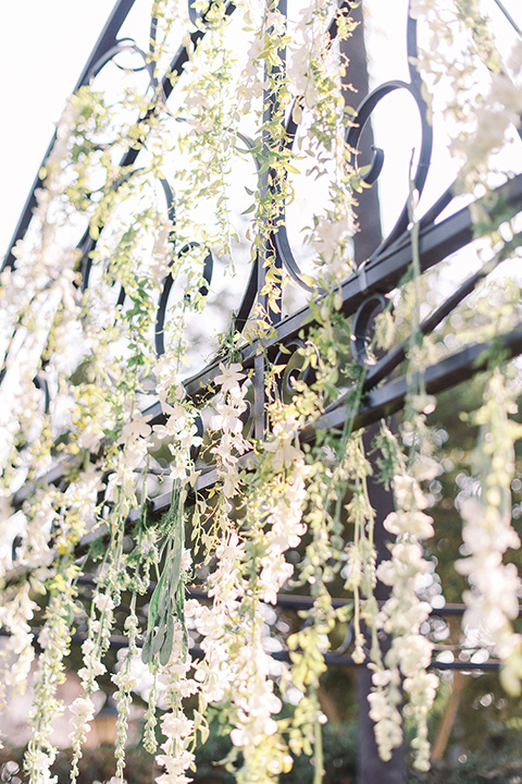  a romantic garden wedding at a Spanish inspired venue with the bride in a lace gown and the groom in a tan suit – ceremony flowers 