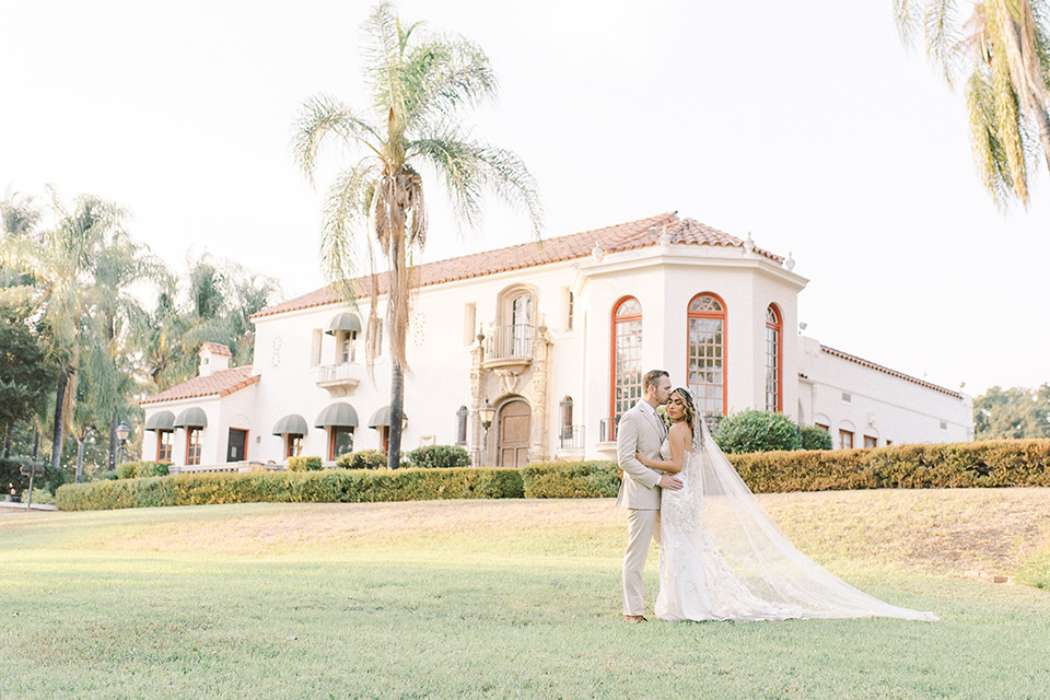  a romantic garden wedding at a Spanish inspired venue with the bride in a lace gown and the groom in a tan suit – couple walking