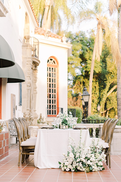  a romantic garden wedding at a Spanish inspired venue with the bride in a lace gown and the groom in a tan suit – table seating and décor 