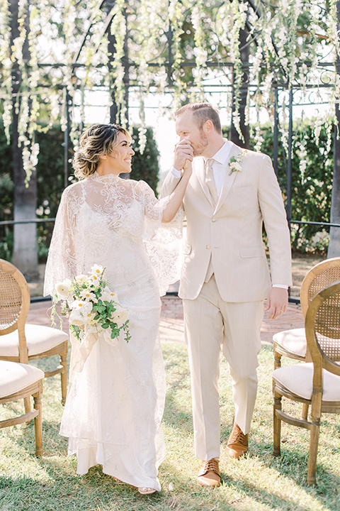  a romantic garden wedding at a Spanish inspired venue with the bride in a lace gown and the groom in a tan suit – couple at the ceremony 