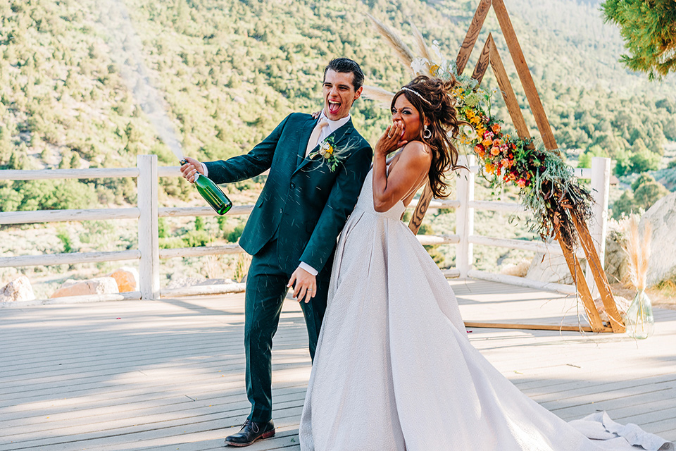  a greenery las vegas wedding at a rustic venue with the bride in an A-line gown and the groom in a green suit – couple with champange