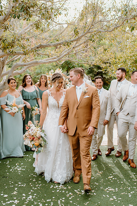  earth-toned boho wedding with the bridesmaids in green dresses, groomsmen in tan suits, and the groom in a caramel suit – bridalparty 