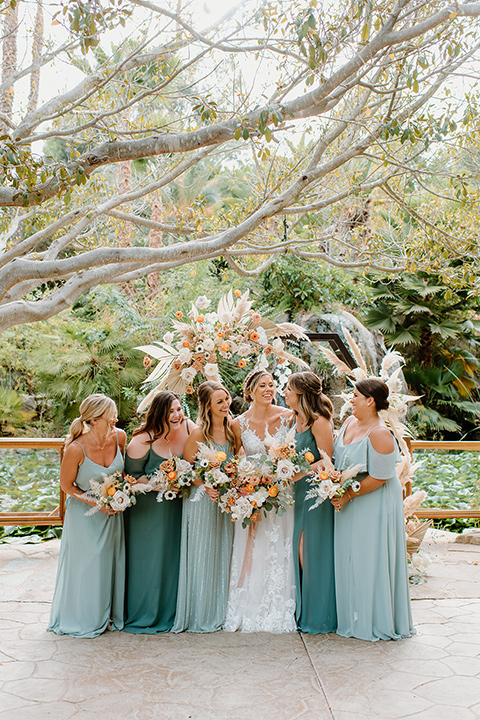  earth-toned boho wedding with the bridesmaids in green dresses, groomsmen in tan suits, and the groom in a caramel suit – bridesmaids
