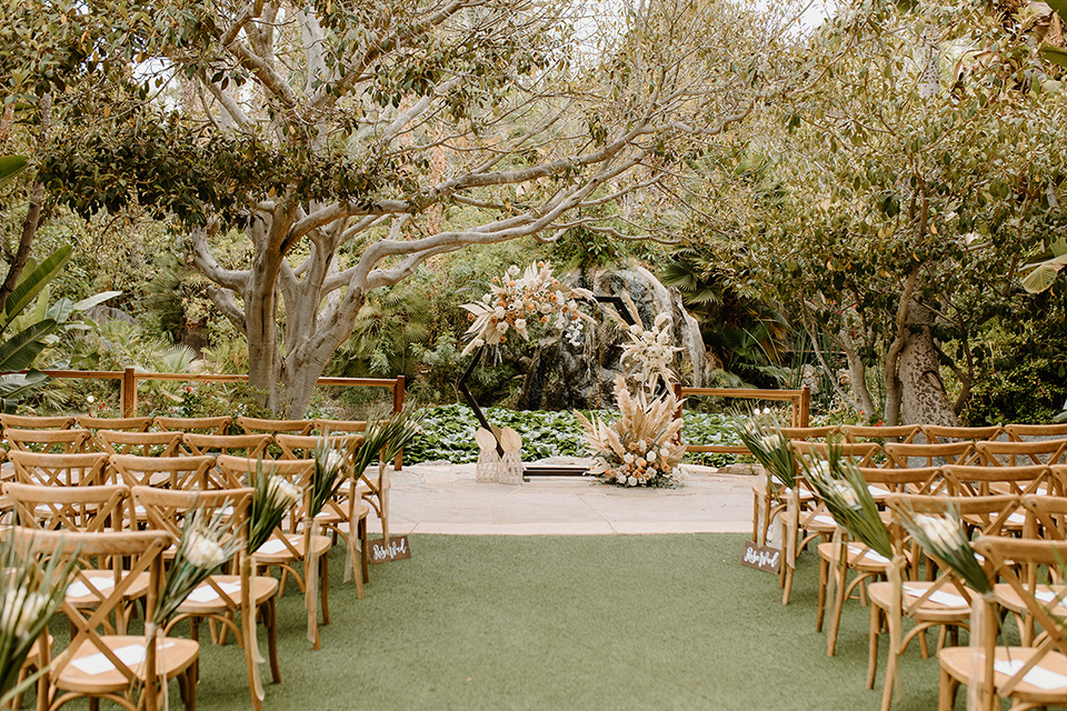  earth-toned boho wedding with the bridesmaids in green dresses, groomsmen in tan suits, and the groom in a caramel suit – ceremony decor