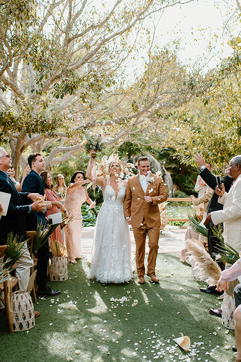  earth-toned boho wedding with the bridesmaids in green dresses, groomsmen in tan suits, and the groom in a caramel suit – ceremony celebration