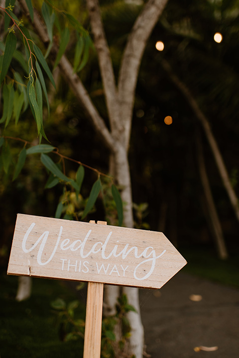  earth-toned boho wedding with the bridesmaids in green dresses, groomsmen in tan suits, and the groom in a caramel suit – reception signage