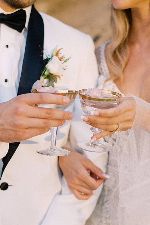  beach side wedding with the bride in a flowing lace gown and the groom in a white tuxedo – cheersing