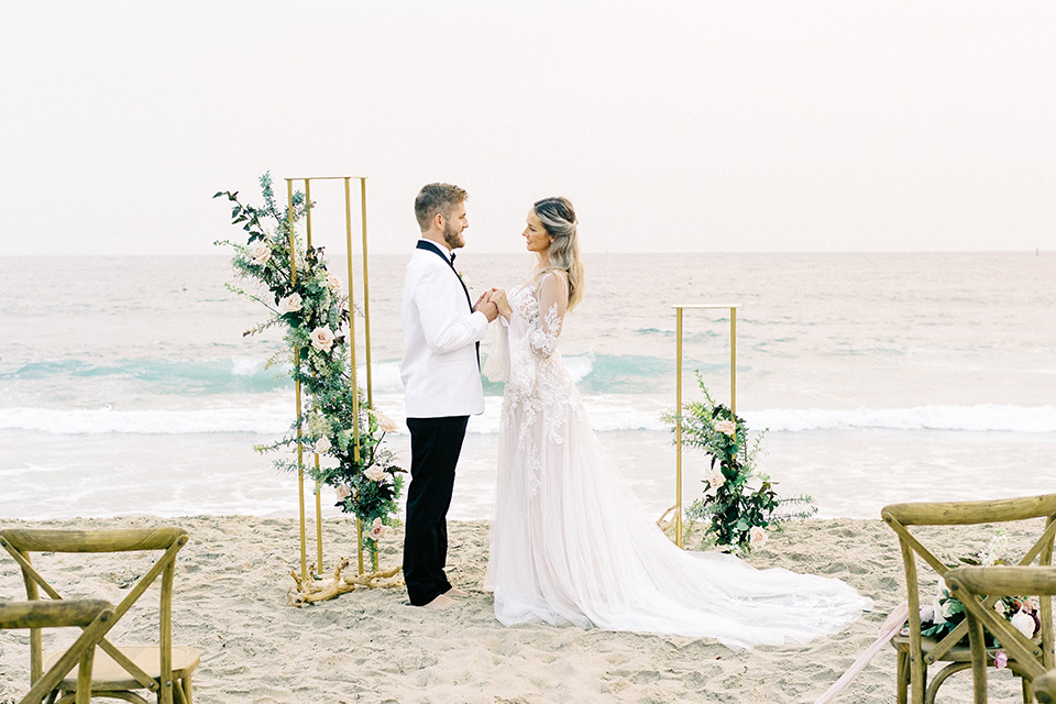  beach side wedding with the bride in a flowing lace gown and the groom in a white tuxedo – vows