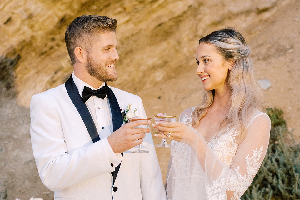 beach side wedding with the bride in a flowing lace gown and the groom in a white tuxedo – cheersing