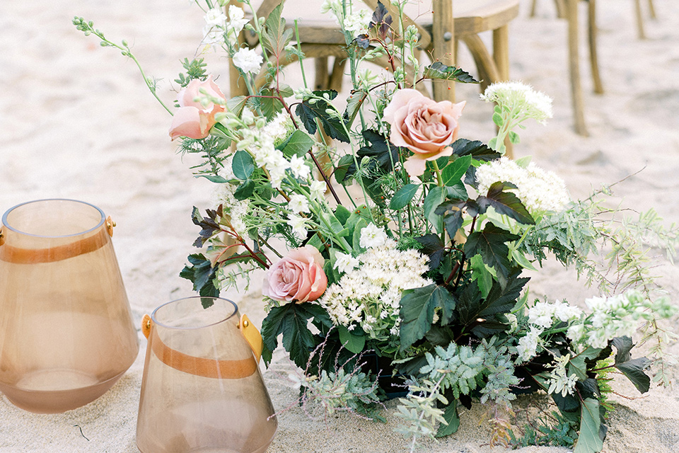  beach side wedding with the bride in a flowing lace gown and the groom in a white tuxedo – flowers on the table