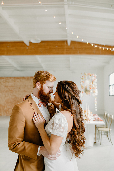  an amber toned wedding in san diego california with the bride in a modern fitted gown with cap sleeves and the groom in a caramel suit – couple at the reception 