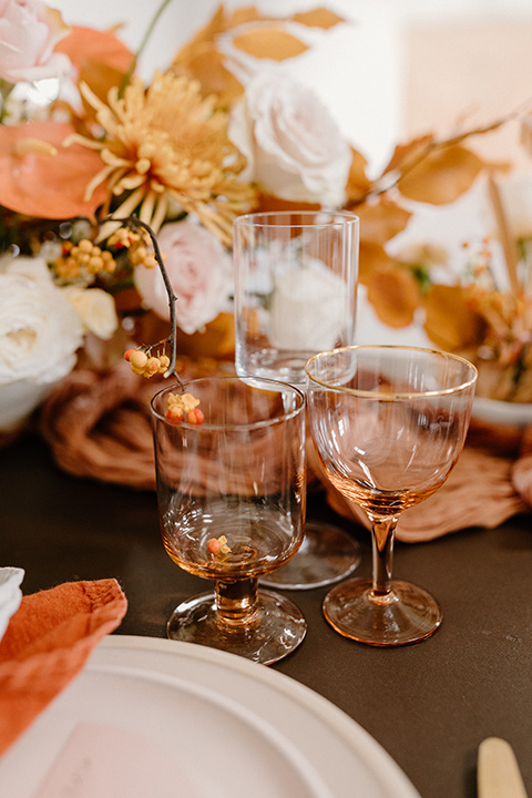  an amber toned wedding in san diego california with the bride in a modern fitted gown with cap sleeves and the groom in a caramel suit – amber drinkware on the reception tables 