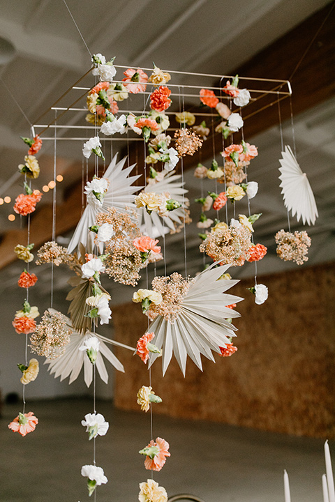  an amber toned wedding in san diego california with the bride in a modern fitted gown with cap sleeves and the groom in a caramel suit – hanging flowers above the reception tables 