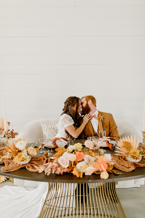  an amber toned wedding in san diego california with the bride in a modern fitted gown with cap sleeves and the groom in a caramel suit – couple at sweetheart table 