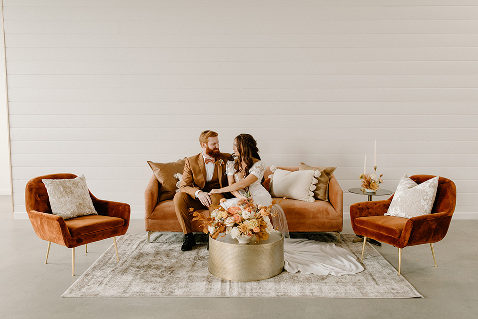  an amber toned wedding in san diego california with the bride in a modern fitted gown with cap sleeves and the groom in a caramel suit – furniture in the reception