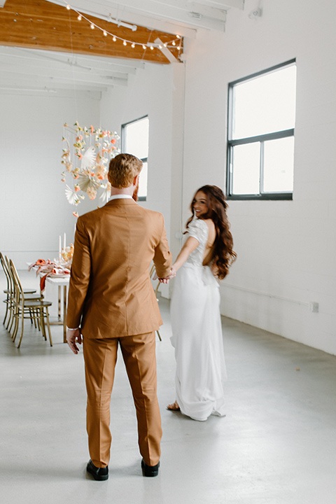  an amber toned wedding in san diego california with the bride in a modern fitted gown with cap sleeves and the groom in a caramel suit – couple at the reception 