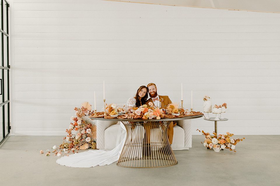  an amber toned wedding in san diego california with the bride in a modern fitted gown with cap sleeves and the groom in a caramel suit – sweetheart table