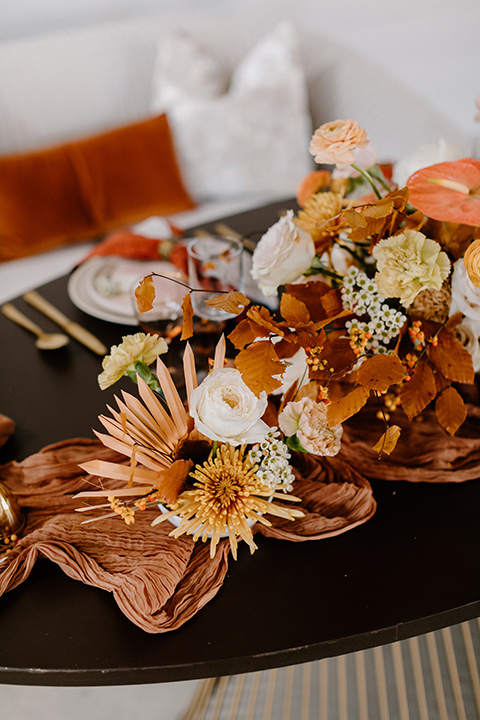  an amber toned wedding in san diego california with the bride in a modern fitted gown with cap sleeves and the groom in a caramel suit – florals on the tables at the reception 