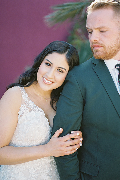  museum of latin american art wedding with 2 different styles – one bride in a fitted gown and the groom in a grey suit and the other bride in a lace gown and the groom in a green suit – close up on the bride hugging groom 