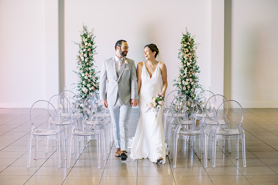  museum of latin american art wedding with 2 different styles – one bride in a fitted gown and the groom in a grey suit and the other bride in a lace gown and the groom in a green suit – couple at ceremony