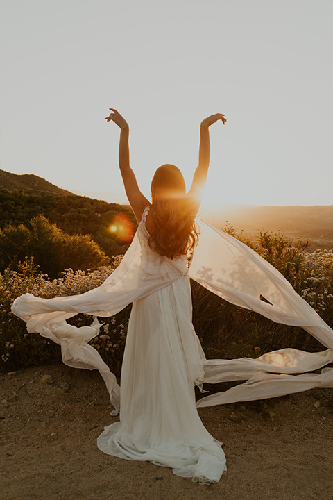  wildflower wedding in a field with the bride in a flowing gown and bridal wings, and the groom in a tan suit and bolo tie - bride 