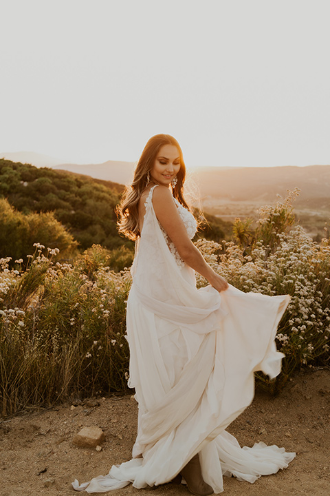  wildflower wedding in a field with the bride in a flowing gown and bridal wings, and the groom in a tan suit and bolo tie - bride