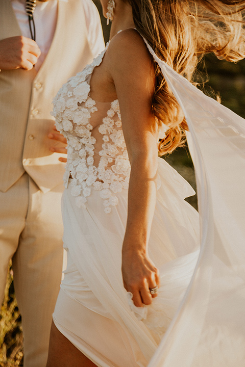  wildflower wedding in a field with the bride in a flowing gown and bridal wings, and the groom in a tan suit and bolo tie – couple embracing