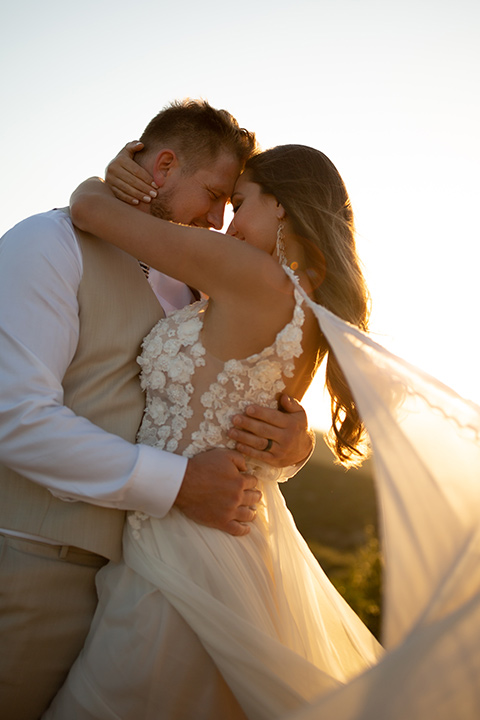  wildflower wedding in a field with the bride in a flowing gown and bridal wings, and the groom in a tan suit and bolo tie – couple embracing