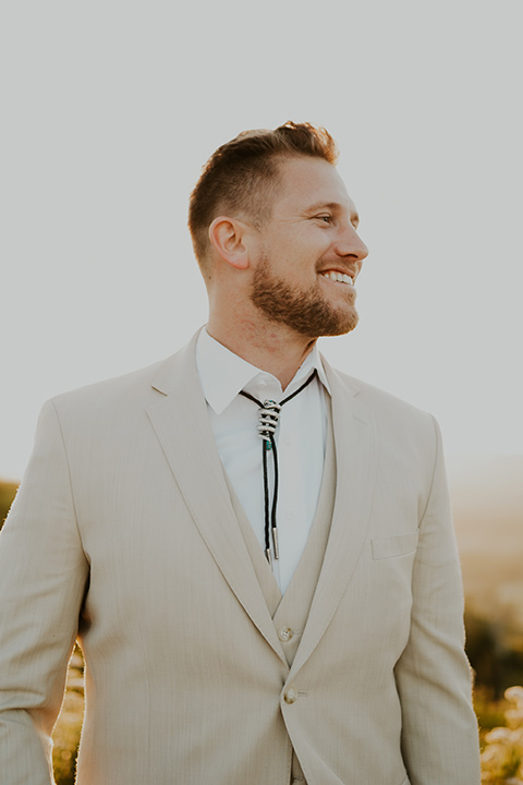  wildflower wedding in a field with the bride in a flowing gown and bridal wings, and the groom in a tan suit and bolo tie - groom 