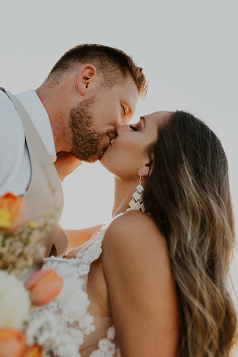  wildflower wedding in a field with the bride in a flowing gown and bridal wings, and the groom in a tan suit and bolo tie - couple embracing 