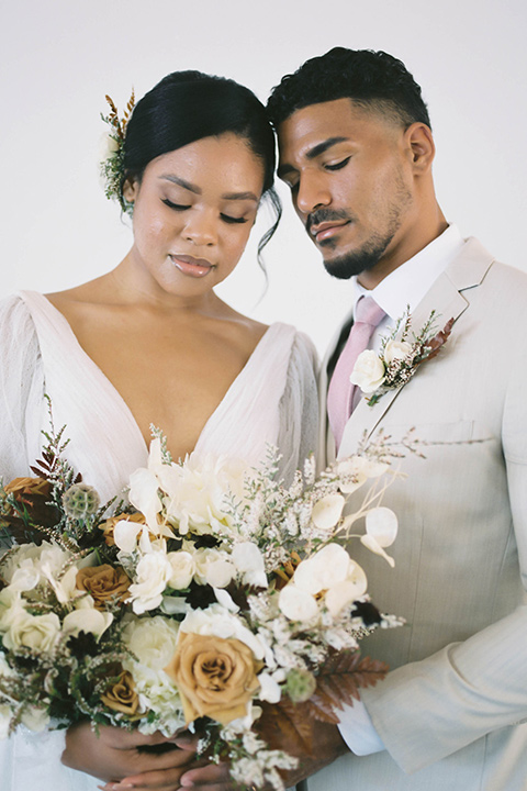  minimalistic nude wedding with vintage touches, the bride in a flowing gown with sleeves and the groom in a tan suit – couple touching heads