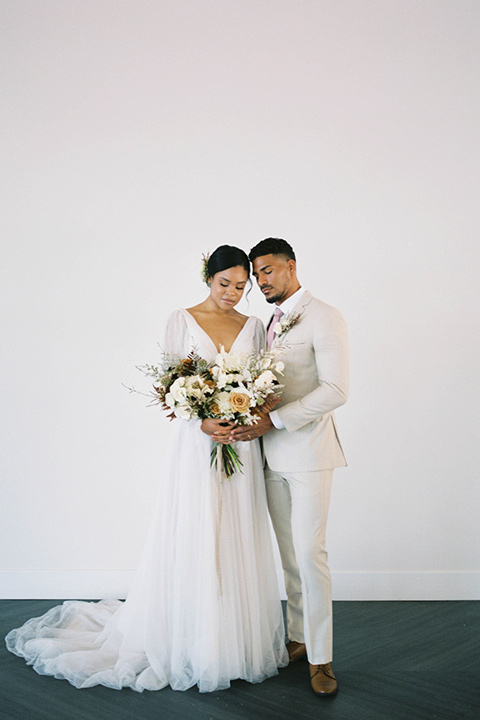  minimalistic nude wedding with vintage touches, the bride in a flowing gown with sleeves and the groom in a tan suit – embracing 