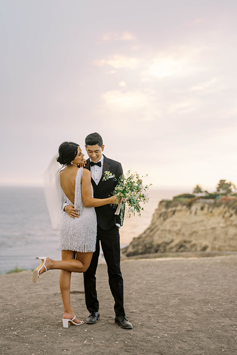  modern black and white upscale wedding on the cliffs overlooking the ocean – bride in short dress and couple on the sand 