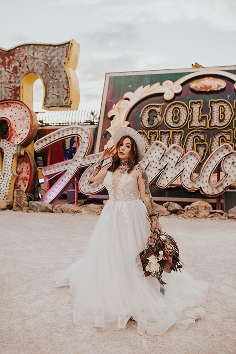  same sex wedding with two brides at the neon museum in las vegas with one brief is a bohemian ballgown and the other in a gold velvet tuxedo coat and tan pants – bride in dress and leather coat 