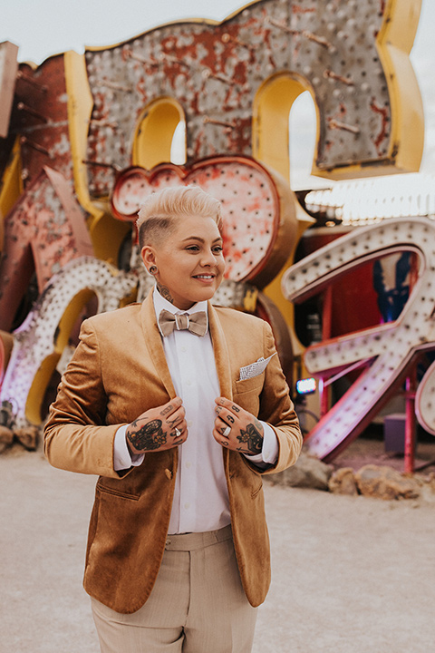  same sex wedding with two brides at the neon museum in las vegas with one brief is a bohemian ballgown and the other in a gold velvet tuxedo coat and tan pants – bride in gold velvet tuxedo and tan pants