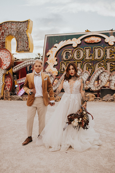  same sex wedding with two brides at the neon museum in las vegas with one brief is a bohemian ballgown and the other in a gold velvet tuxedo coat and tan pants – couple dancing