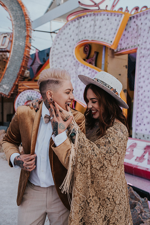  same sex wedding with two brides at the neon museum in las vegas with one brief is a bohemian ballgown and the other in a gold velvet tuxedo coat and tan pants – couple dancing