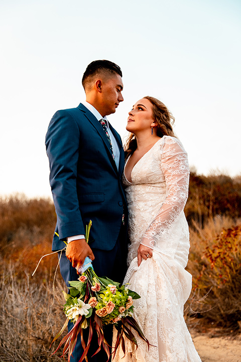  newport wedding in the cliffs with the bride in a lace gown and the groom in a navy blue suit – couple looking at each other