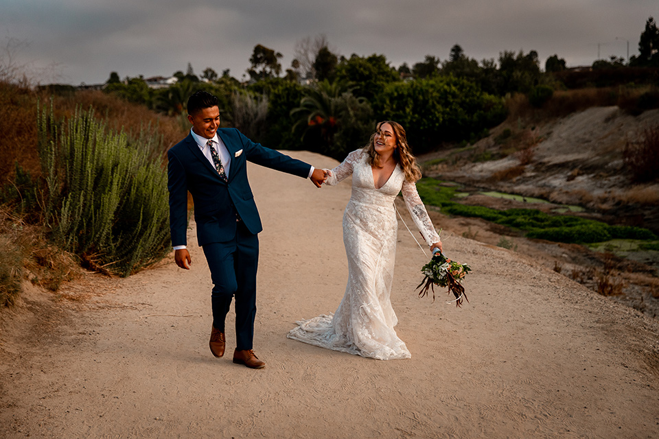  newport wedding in the cliffs with the bride in a lace gown and the groom in a navy blue suit – holding hands and dancing 