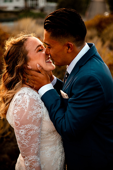  newport wedding in the cliffs with the bride in a lace gown and the groom in a navy blue suit – couple holding hands