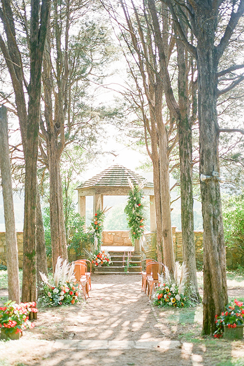  blush and burgundy wedding in the woods with the bride in a boho lace gown, the groom in a burgundy shawl tuxedo, and the bridesmaids in a dusty blush velvet gown – ceremony decor