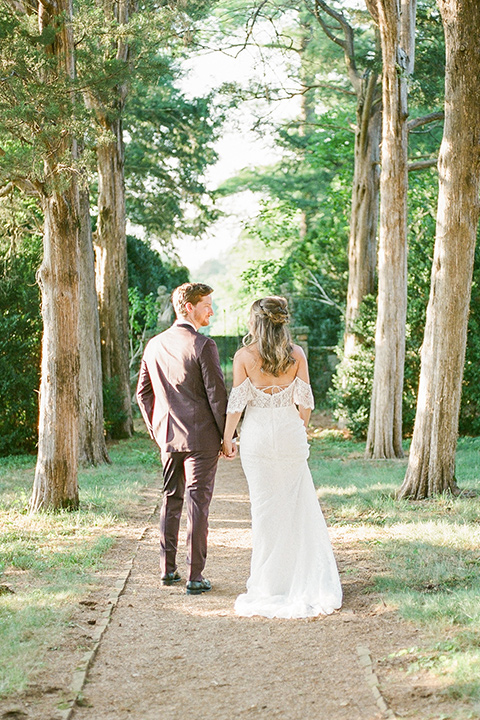  blush and burgundy wedding in the woods with the bride in a boho lace gown, the groom in a burgundy shawl tuxedo, and the bridesmaids in a dusty blush velvet gown – walking in the woods
