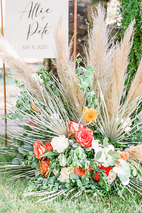  blush and burgundy wedding in the woods with the bride in a boho lace gown, the groom in a burgundy shawl tuxedo, and the bridesmaids in a dusty blush velvet gown – florals