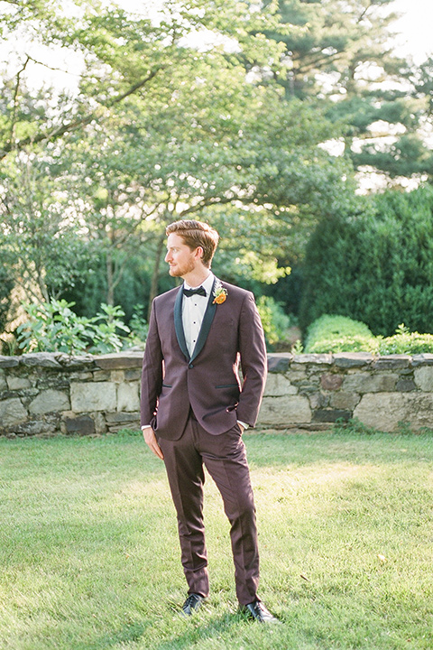  blush and burgundy wedding in the woods with the bride in a boho lace gown, the groom in a burgundy shawl tuxedo, and the bridesmaids in a dusty blush velvet gown – groom