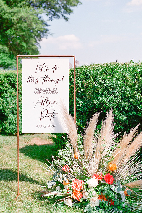  blush and burgundy wedding in the woods with the bride in a boho lace gown, the groom in a burgundy shawl tuxedo, and the bridesmaids in a dusty blush velvet gown – signage