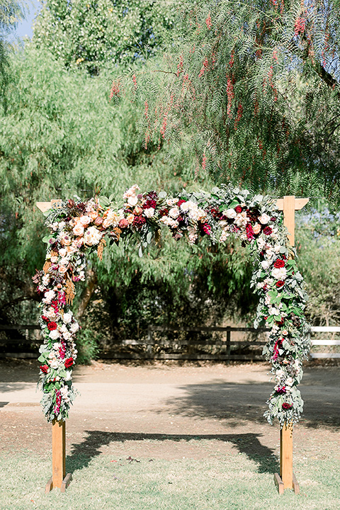  a lavender and black wedding in a garden – with the bride in a long sleeve lace gown and the groom in a black tuxedo – ceremony altar 